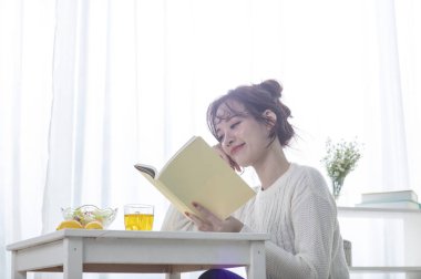 Genç bir kadın mutfakta kitap okuyor.