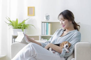 Yanında köpek olan Asyalı kız dijital tablet kullanıyor.