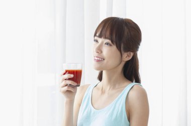 Genç bir kadın kırmızı meyve suyu içiyor.