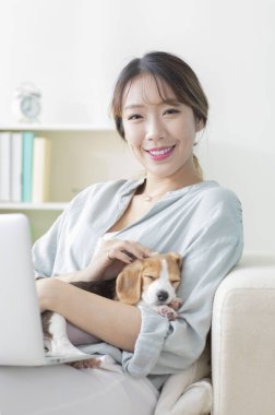 Köpeği yakınlardayken dizüstü bilgisayar kullanan mutlu bir kadın.