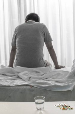 Hasta yaşlı bir adamın yatakta oturduğu arka manzara.