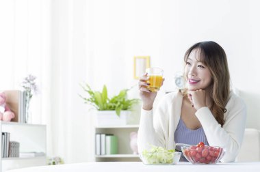 Mutlu Asyalı kız kahvaltı yapıyor. 