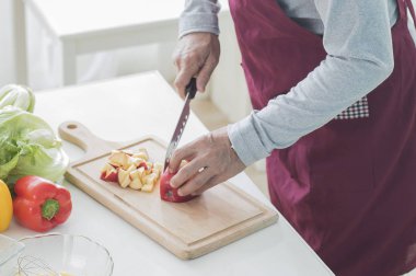Adam evdeki masada sebze pişiriyor.