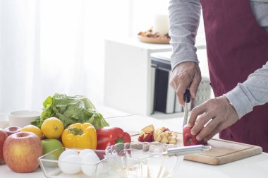 Adam evdeki masada sebze pişiriyor.