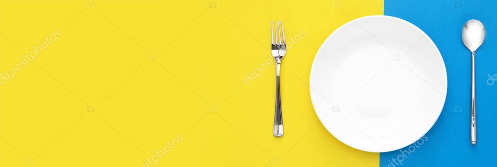 fork, spoon and white plate on color background