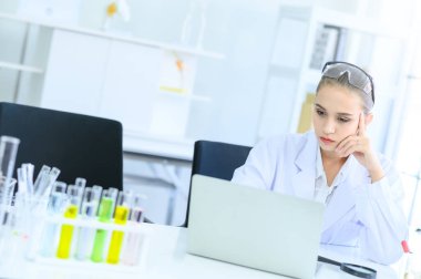 Genç bilim kadını, laboratuarda dizüstü bilgisayarla bir deney ya da araştırma yapıyor. Tıbbi sağlık teknolojisi, farmasötik araştırma ve geliştirme kavramı.