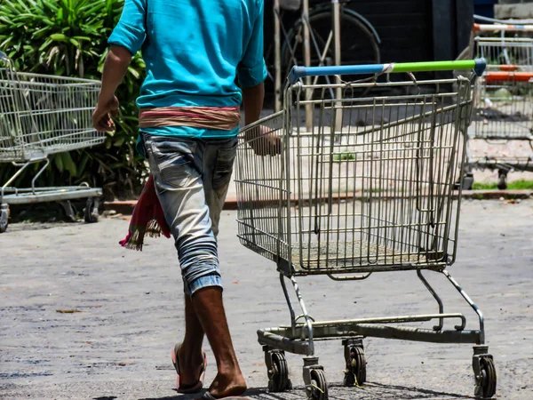 Chłopiec Spacerujący Pustym Wózkiem Przed Supermarketem — Zdjęcie stockowe