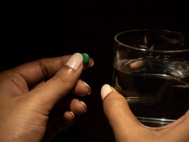 Siyah arka planda iki parmağı olan ilaç ya da ilaç bulundurmak.