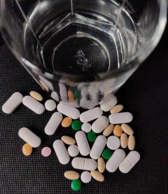 Masadaki ilaç tabletlerini, hapları ve su bardaklarını kapatın..