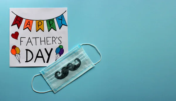 Tebrik kartı Mutlu Babalar Günü ve baba için hediye olarak bir çocuk tarafından çizilmiş bıyıklı koruyucu yüz maskesi. Violet geçmişi. Koronavirüs salgını bağlamında Babalar Günü kavramı