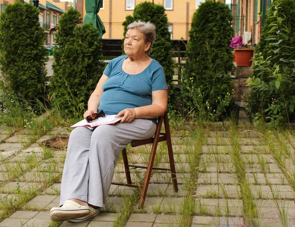 Una Anciana Está Sentada Patio Día Verano Leyendo Libro Veces — Foto de Stock