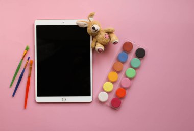 Moskova, Rusya - 19 Nisan 2020: Apple 'dan siyah ekranlı tablet iPad Pro yumuşak oyuncak tavşan, çok renkli boya ve sanat fırçaları mor arkaplanda