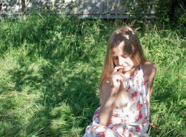 Sarışın kız bahçedeki parlak yeşil çimlerin üzerinde gözleri kapalı oturuyor. O, güneşten ve yazdan hoşlanır. Mutlu çocukluk, güneşli yaz, hoş anılar ve duygular.