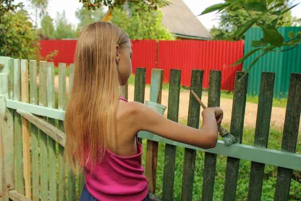 Sarışın reşit olmayan kız çiti fırçayla yeşile boyuyor. Ev tadilatı ve aile kavramına yardım. Yaşam biçimi