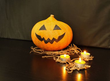 Siyah arka planda yanan mumların yanında çocuklar tarafından yapılmış balkabağı kabağı. Cadılar Bayramı partisi için ev dekorasyonu süreci. 