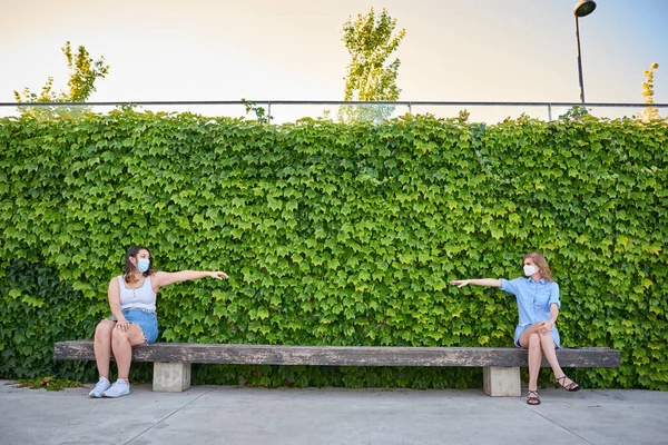 Zwei Frauen Sitzen Getrennt Voneinander Auf Einer Parkbank Und Tragen — Stockfoto