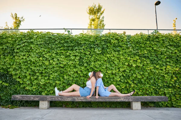 Zwei Maskierte Frauen Sitzen Rücken Rücken Auf Einer Parkbank Sie — Stockfoto