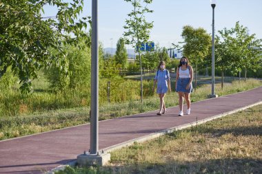 Hapisten sonra iki arkadaş parkta yürümekten zevk alır. Resimde bir metin için yer var.