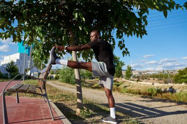 Afrikalı sporcu güneşli bir yaz günü esneme hareketleri yapıyor. O bir şehir parkında. Bir metin için resim alanı var