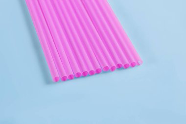 Mavi arka plandaki içecekler için pembe plastik borular.