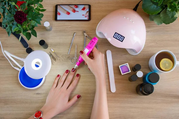 Girl treats nails with a manicure machine. Nail polish, tools for manicure. Ultraviolet lamp. Manicure at home.