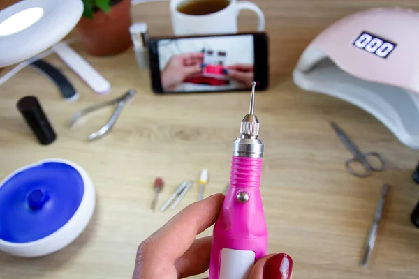 Manicure machine. The girl holds in her hand. Manicure at home.