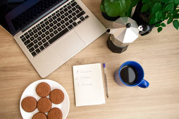 Kahveyle günaydın. Mavili bir fincan kahve. Bisküviler. Kahve makinesi. Günlük rutin bir not. Not Defteri