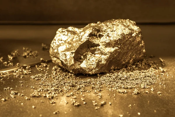 Altın arka planda altın bir taş. Tozlu toz.