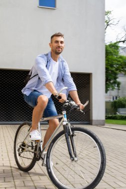 Sırt çantalı bir adam bisiklet sürüyor..