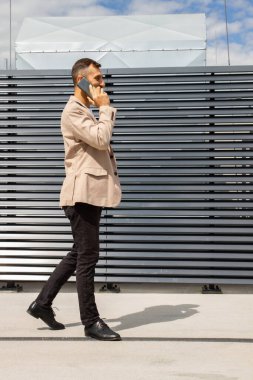 Ceketli genç bir adam telefonda konuşuyor..