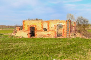 Çayırın ortasında harabe bir tuğla ev.