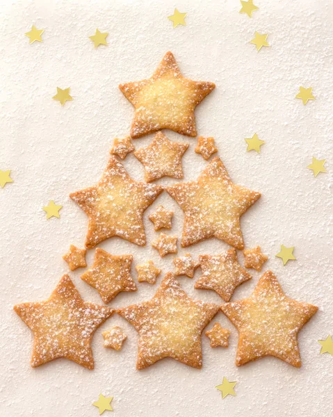 Christmas tree of a star cookie sprinkled with powdered sugar on a white background, top view
