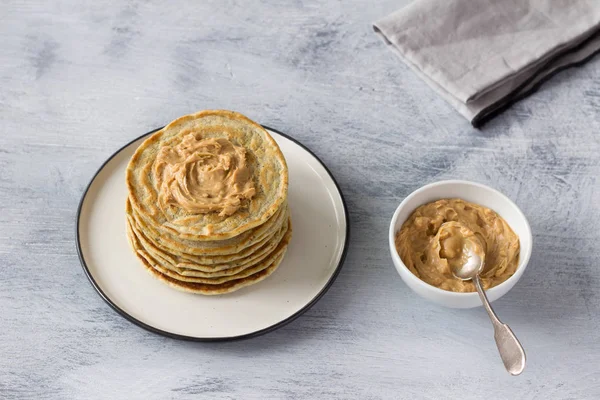 Vegan pancakes with flax seeds and peanut butter on gray background