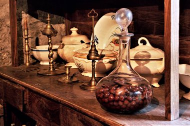 Galiçya 'nın etnoğrafya müzesindeki kırsal bir evin mutfağında eski ahşap dolap, çanak çömlek, tabak, çeşme ve kiraz likörlü cam kavanoz.,