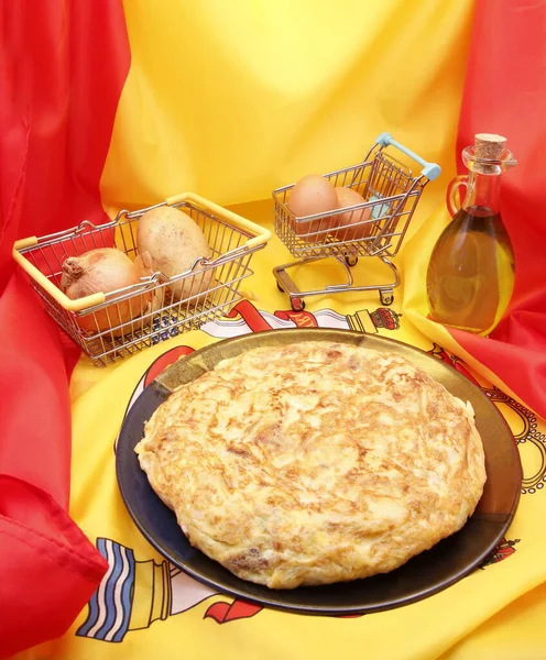 Products from Spain, vertical photograph of the Spanish potato omelette, ingredients, extra virgin olive oil, eggs, potatoes and onion, on the flag of Spain, product photography, natural medicine,