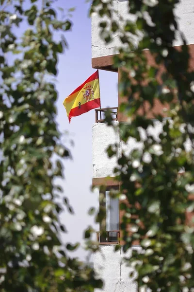 Spain in mourning, Spain flag with crepe or black ribbon, waving in the wind on a balcony representing grief over the death of people by covid-19