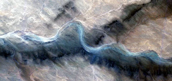 uzun ve eğri yol, Afrika çöllerinin havadan görünüşü, çöl manzaralarının havadan görünüşü, türü: soyut doğalcılık, mecazi, çağdaş fotoğraf, stok fotoğrafı,