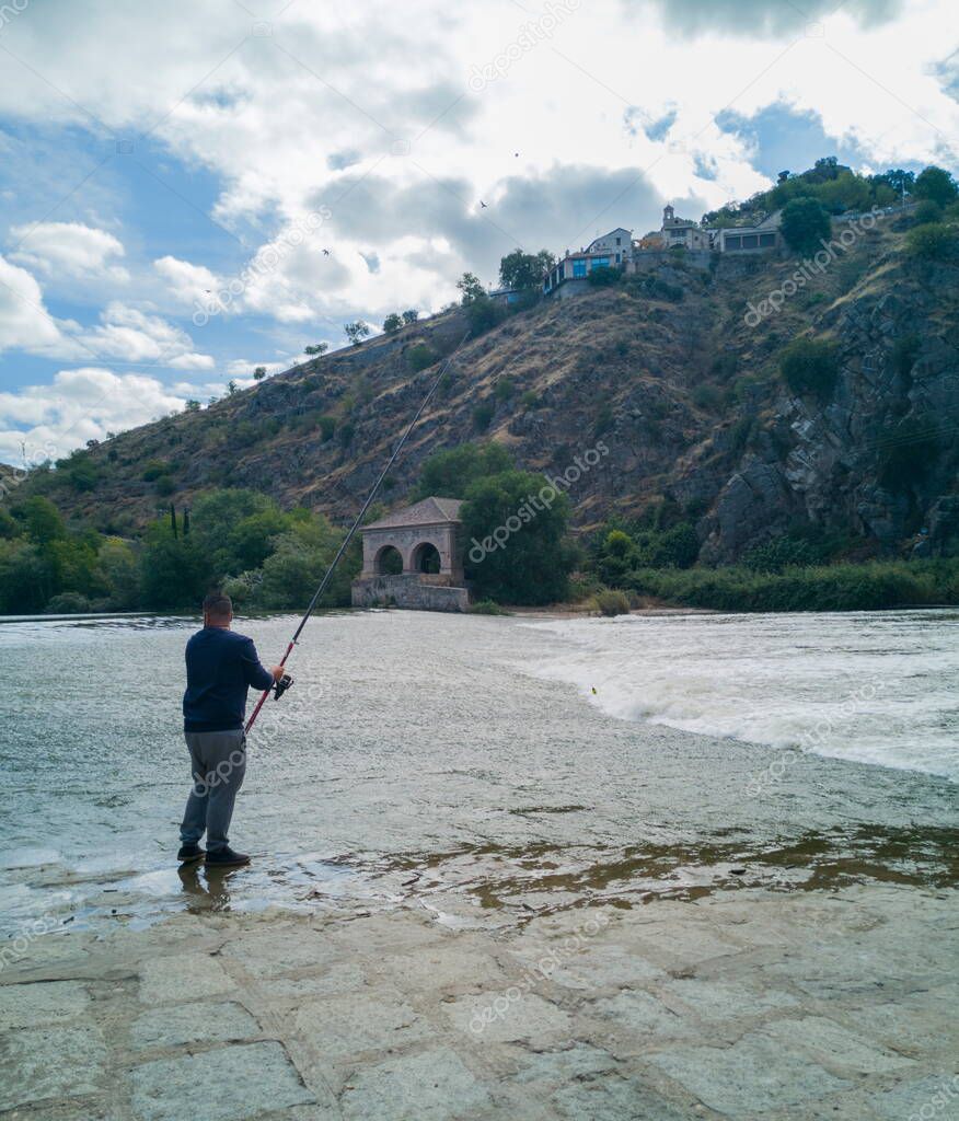 photograph of fisherman in a dam of the Tagus river as it passes through Toledo, Spain,