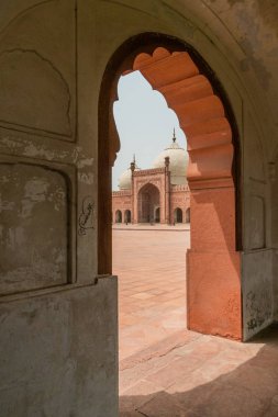 Badshahi Mosque viewed through arch in arcade  in Lahore, Pakistan. Popular tourist attraction. clipart