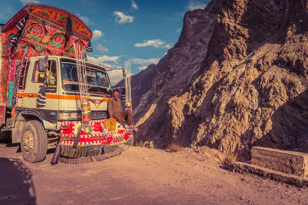 2018年7月19日 巴基斯坦卡拉科兰公路 Karakoram Highway Pakistan 在危险的山路上乘坐装饰卡车前保险杠的巴基斯坦男子 说明性编辑 图库照片
