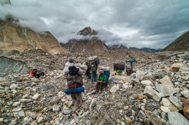 Karakoram, Pakistan - 24 Temmuz 2018: Ağır yükleri olan Şerpalar Pakistan 'daki Karakoram Dağları' nda dinleniyor. İllüstrasyon Editörü.