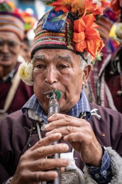 Ladakh, Hindistan - 4 Eylül 2018: Ladakh festivalinde flüt çalan geleneksel şapkalı yerli adam. İllüstrasyon Editörü.