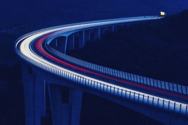 Küresel ulaşım ve lojistik bağlantı. Modern ve gelecekçi otoyolda yoğun trafik var. Yüksek eğimli köprü, günbatımında mühendislik başyapıtı.