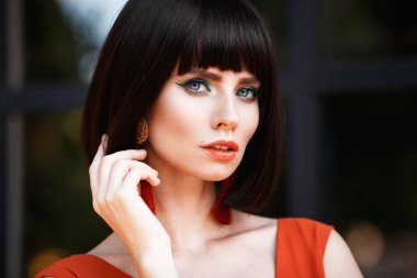 Güzel yakın çekim portre toyng kadın moda küpe ve uzun drees retro vintage tarzı. Parlak renkli makyaj ve stilysh saç kesimi. Dış sokak fotoğraf.