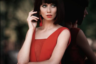 Güzel yakın çekim portre toyng kadın moda küpe ve uzun drees retro vintage tarzı. Parlak renkli makyaj ve stilysh saç kesimi. Dış sokak fotoğraf.