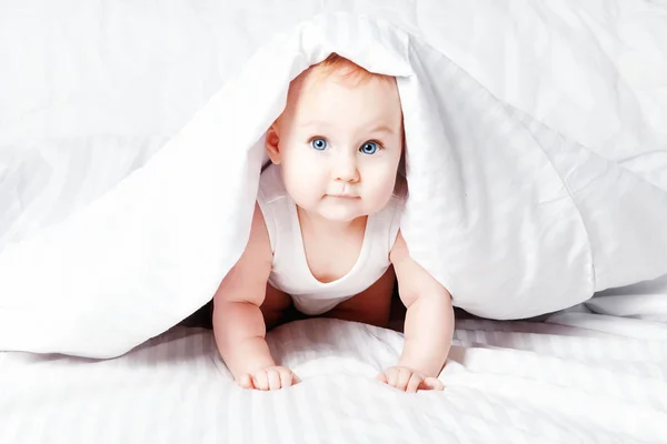 可爱又搞笑的小宝宝微笑下白色的毯子 复制空间 — 图库照片