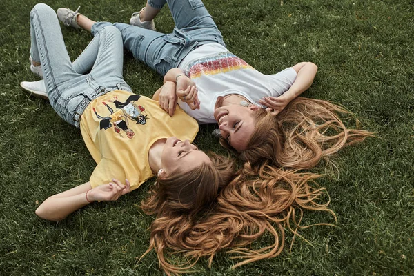 İki mutlu genç kadın çim üzerinde moda shi giyen eğlenmek — Stok fotoğraf