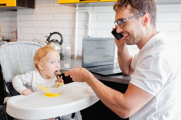 Feliz padre joven trabajando en casa y sentado con una niña . — Foto de Stock