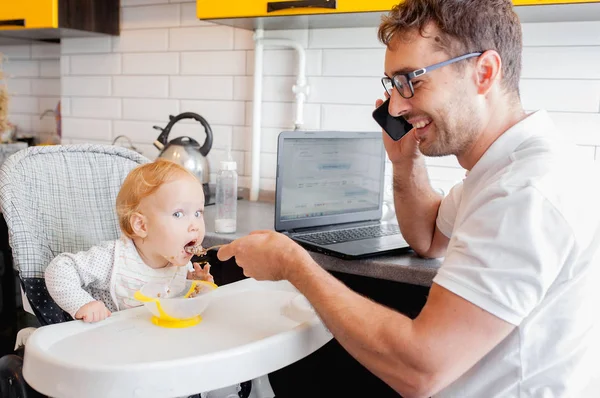 Feliz padre joven trabajando en casa y sentado con una niña . — Foto de Stock