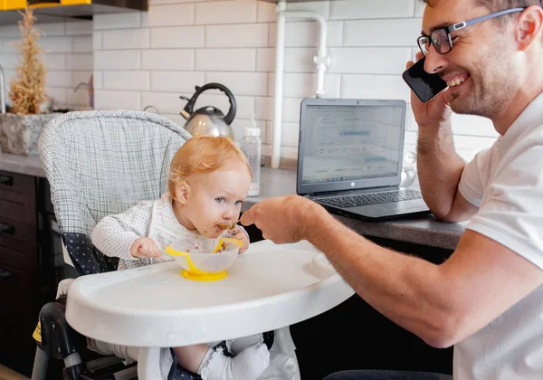 Happy young father working at home and sitting with a baby girl.